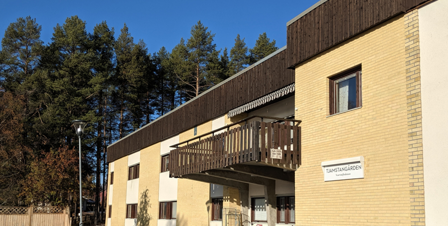 Äldreboendet Tjamstangården. Ett tvåvåningshus med gult tegel och vita fält på fasaden.