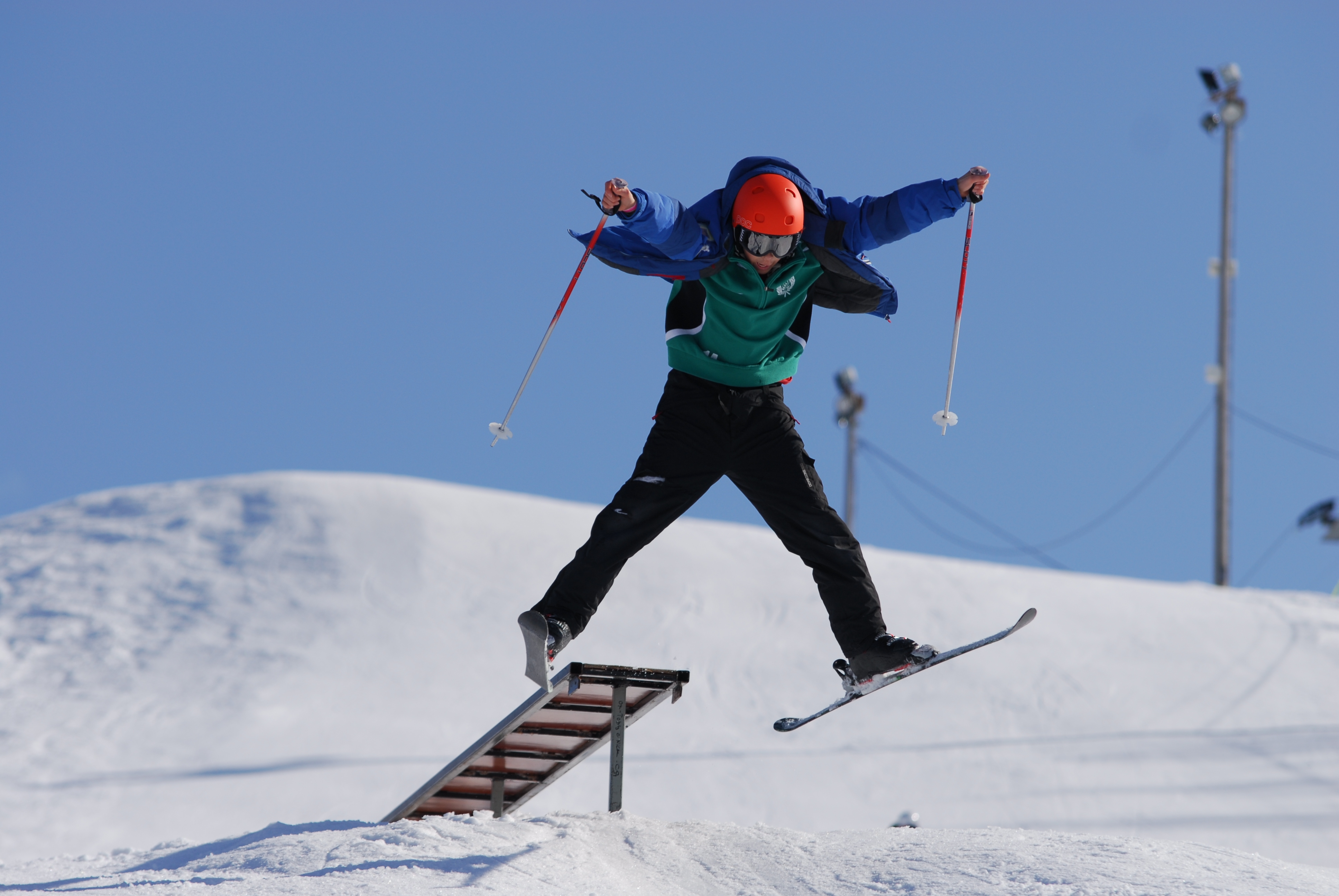 Pojke som hoppar med sina slalomskidor i Tjamstanbackarna. Himlen är klarblå.