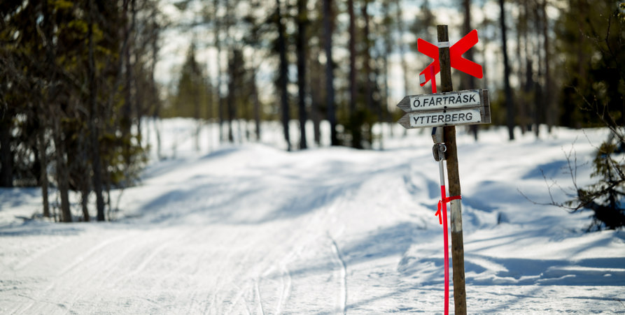 Skoterled med reflexpinne och skylt som hänvisar till Östra Fårträsk och Ytterberg. 
