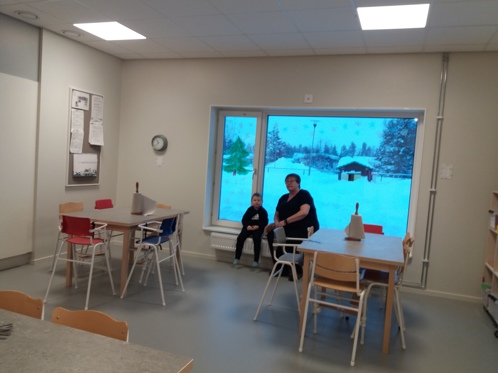 Kvinnlig förskolelärare sitter med ett barn vid ett fönster vid nya förskolan på Tjambo.